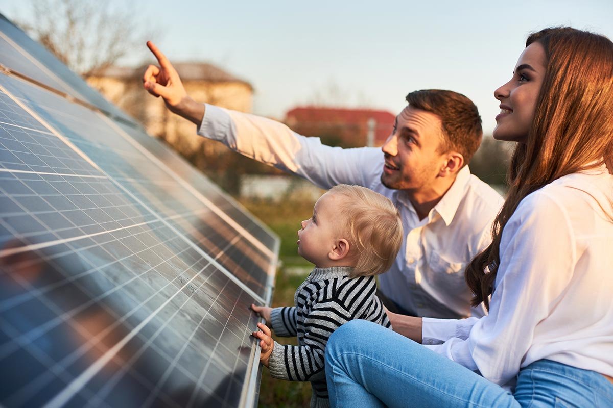 Family with child examining solar panels in a garden, highlighting the benefits of combining electric vehicles with solar systems by LA Solar Group.