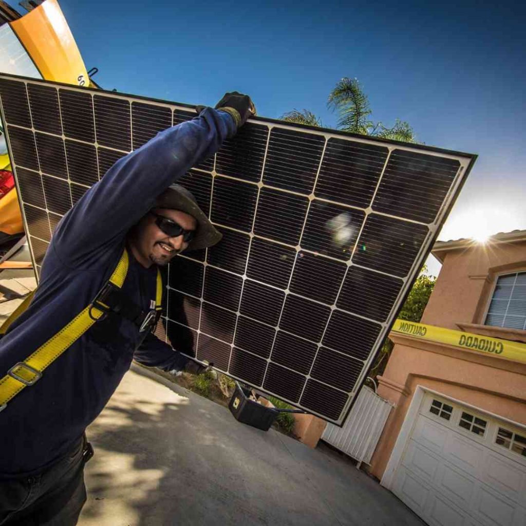 Photo of LA Solar Group installer carrying a solar panel