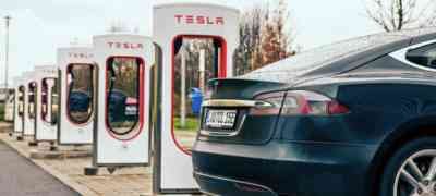 Tesla electric car charging at a row of Tesla Supercharger stations, promoting sustainable energy solutions, relevant to LA Solar Group's commercial services.